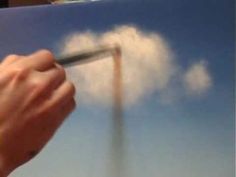 a hand holding a pen writing on a piece of paper with clouds in the background