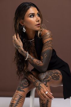 a woman with tattoos on her body sitting in a chair and posing for the camera