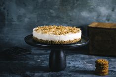 a cake with crumbs on it sitting on a black plate next to cookies