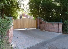 a brick driveway with a wooden fence and gate