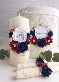 two wedding candles with red, white and blue flowers on them next to a candle holder