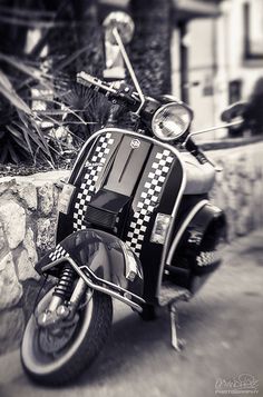 a motor scooter with checkered seat covers is parked on the side of the road