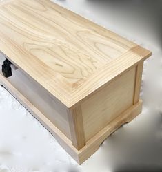 a large wooden box sitting on top of a white tablecloth covered floor next to a black object