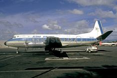 an airplane is parked on the tarmac with other planes in the background and clouds in the sky