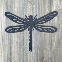 a metal dragonfly sitting on top of a wooden table next to a planter