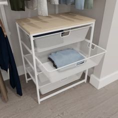 an open closet with clothes hanging on the rack and folded towels in bins next to it