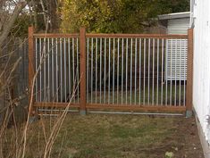 a fenced in yard next to a house with trees and bushes on the other side