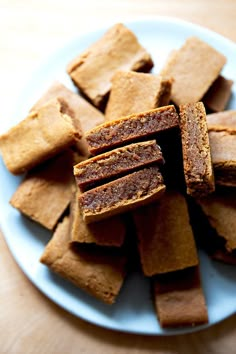 a plate full of brownies cut into squares on top of a wooden tablecloth