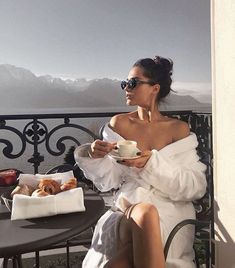 a woman sitting at a table with a cup of coffee and croissants