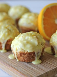 there are muffins with icing next to an orange