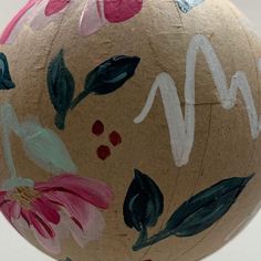 a painted ball with flowers on it sitting on top of a white table next to a wall