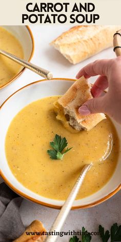 a person dipping some bread into a bowl of carrot and potato soup