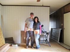 a man and woman standing next to each other in a room with wood flooring