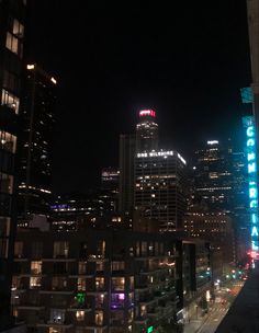 the city skyline is lit up at night with bright lights and buildings in the background