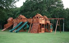 a wooden play set in the middle of a field with a slide and climbing frame