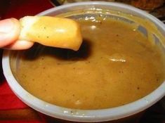 a person is dipping something in a bowl with a spoon into some soup or sauce