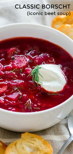 a white bowl filled with beet soup next to crackers