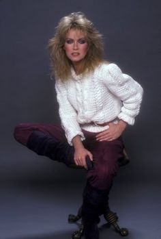 a woman in white sweater and red pants posing with her legs on the ground while wearing black boots