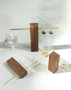 three pieces of wood with earrings on them and a statue in the background, all made out of brass