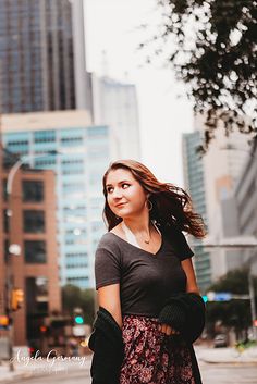 a woman standing in the middle of a street with her hair blowing in the wind