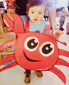 a little boy standing in front of a paper cut out of a crab with big eyes