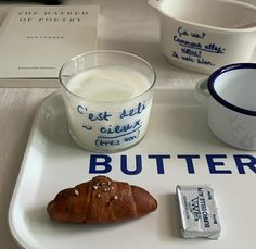 a breakfast tray with butter, yogurt and croissant