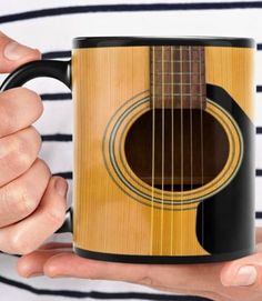 a person holding a coffee mug with a guitar on it