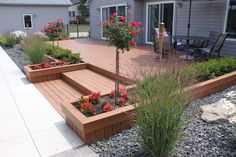 a wooden deck surrounded by plants and flowers