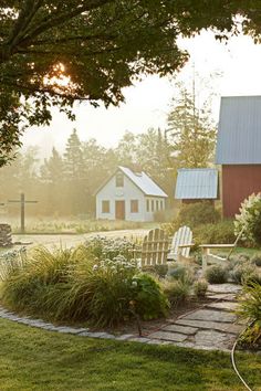 the sun shines brightly in front of a small white house and garden with chairs