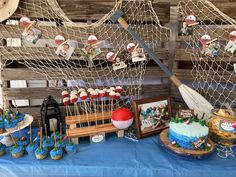 a table topped with cakes and cupcakes covered in frosting next to a net