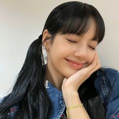 a woman with long black hair smiling and holding her hand to her face while wearing earrings