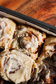 cinnamon rolls with icing in a pan on a wooden table