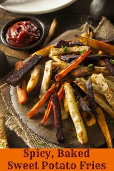 baked sweet potato fries on a wooden plate with ketchup and sauce in the background