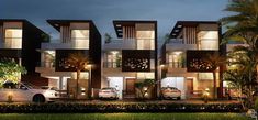 two story townhouses at night with cars parked on the street and palm trees in front