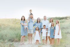 a family posing for a photo on the beach in front of grass and sand dunes