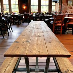 a long wooden table sitting inside of a restaurant