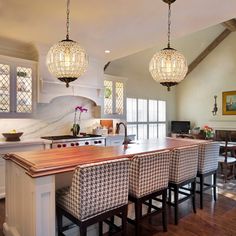 a large kitchen with an island and chandelier hanging from it's ceiling