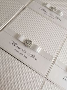 wedding cards with diamond brooches and ribbon on them are displayed in white boxes