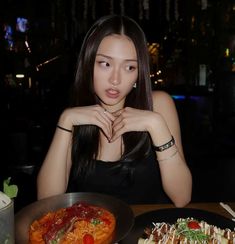 a woman sitting at a table with two plates of food