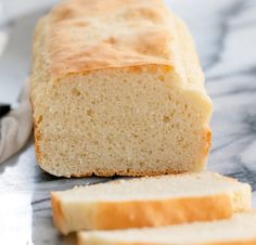 a loaf of bread sitting on top of a counter next to slices of bread and a knife