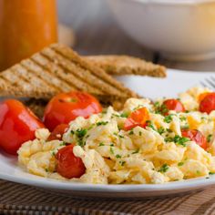 a white plate topped with eggs, tomatoes and crackers