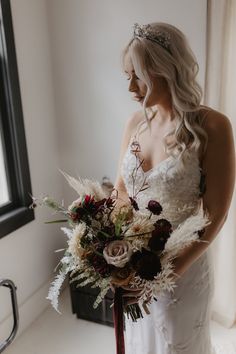 a woman in a wedding dress holding a bouquet and looking out the window with her eyes closed