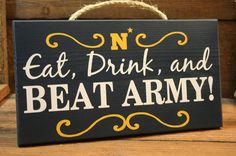 a sign that says eat, drink and beat navy on the side of a wooden table