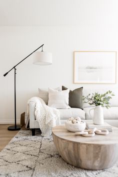 a living room with white couches and pillows on the floor next to a coffee table