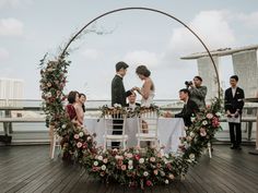 a bride and groom standing at the end of their wedding ceremony in front of an arch decorated with flowers