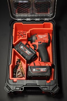 an open tool box with tools in it on a black surface, including drill and screwdriver