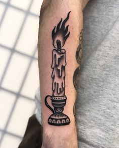 a man with a tattoo on his arm holding a coffee cup in the shape of a candle