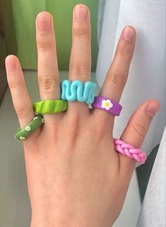 a person's hand with four different colored rings on it and the word mom written in small letters