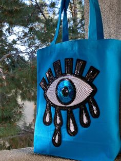 "Evil Eye 100% Cotton  Tote Bag with Gusset. This tote bag is perfect for the beach and everyday essentials. Handmade and High-Quality turquoise gusset canvas fabric. Made from soft material fabric with self-fabric handles. Details:  Length: 13 1/4\" Width: 13 1/4\" Thickness: 3 3/4\" Handle Drop Length: 9\"   Total Length: 20'' Fast and Free shipping from the US 100% Authentic, made by Karens Line PACKAGING -Your purchase will come beautifully packaged. If you are ordering a gift and would like each piece to be packaged separately please let us know.  -If this purchase is a gift, and you would like us to include a handwritten message, please leave a note in the box at checkout." Evil Eye Art, Handmade Evil Eye, Tote Beach Bag, Diy Bags Patterns, Embroidery Bags, Diy Tote Bag, Diy Crafts Jewelry, Beach Tote Bags, Everyday Bag