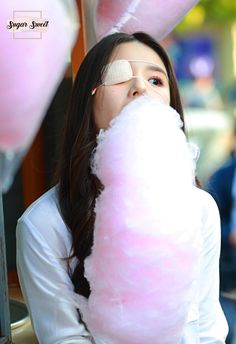 a woman with blindfolded eyes is eating cotton candy